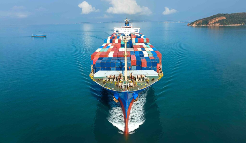 Aerial in front of cargo ship carrying container and running for export goods from cargo yard port to custom ocean concept freight shipping by ship .