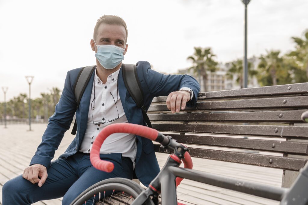 man-with-face-mask-sitting-bench-his-bike-outdoors